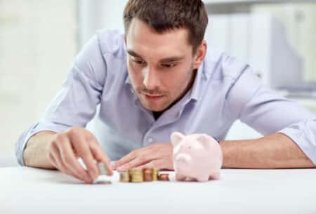 Businessman With Piggy Bank And Coins At Office