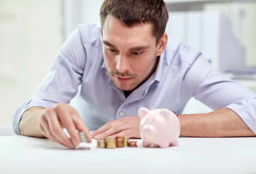 Businessman With Piggy Bank And Coins At Office